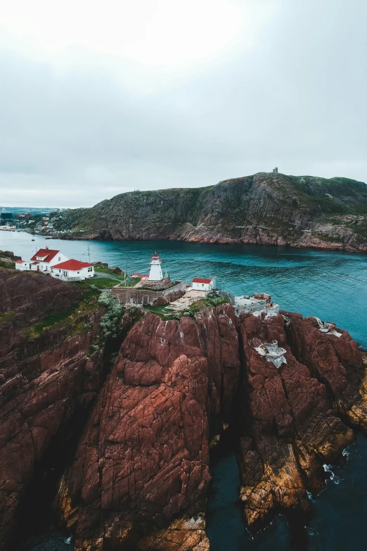 a lighthouse sitting on top of a rocky island, by Daniël Mijtens, pexels contest winner, white buildings with red roofs, quebec, “ aerial view of a mountain, rocky cliffs