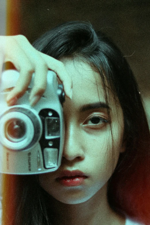 a woman taking a picture of herself with a camera, inspired by Elsa Bleda, photorealism, a young asian woman, film still from a horror movie, infp young woman, loving stare