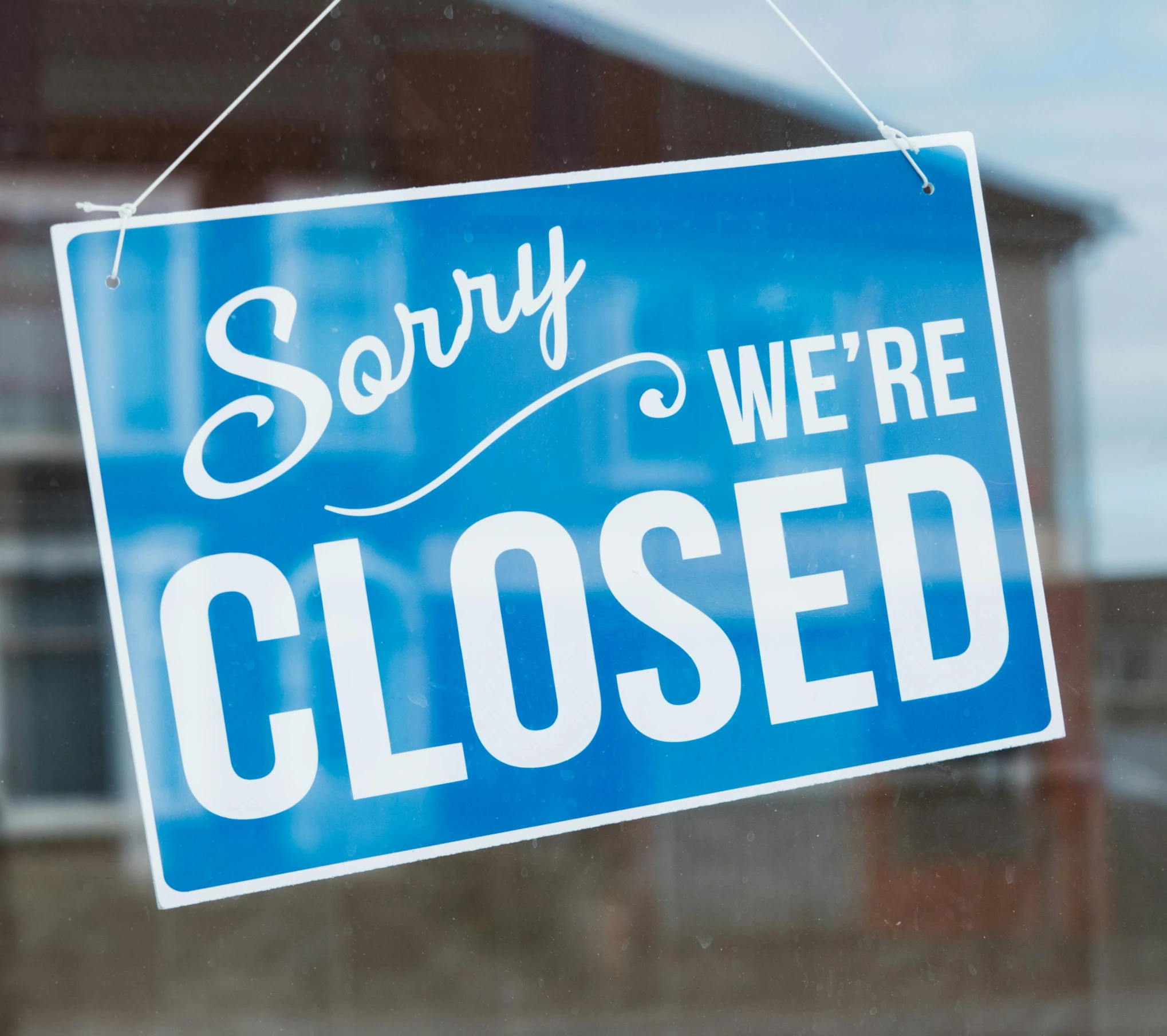 a blue sign that says sorry we're closed, by Rachel Reckitt, gloss finish, medium close shot, holding close, stores