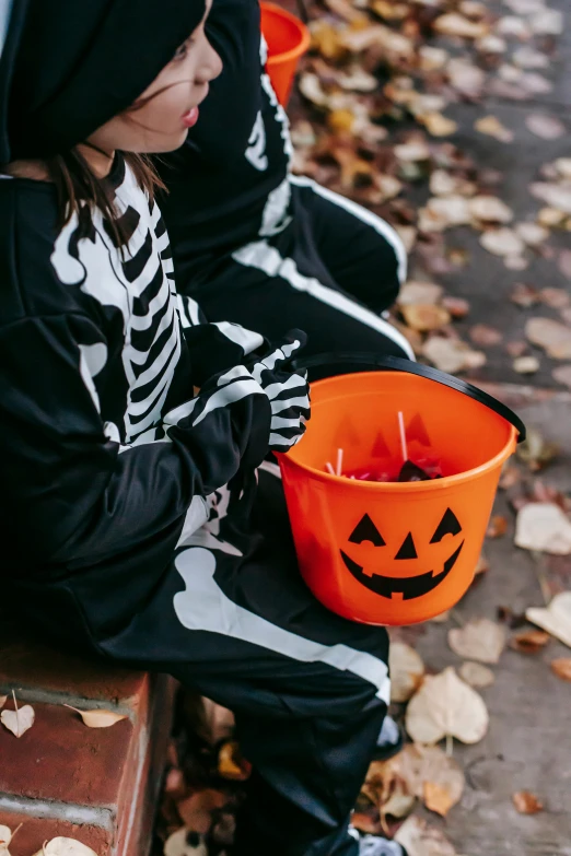two young children dressed up in halloween costumes, by Julia Pishtar, pexels, cup of death, detail shot, candies, bench