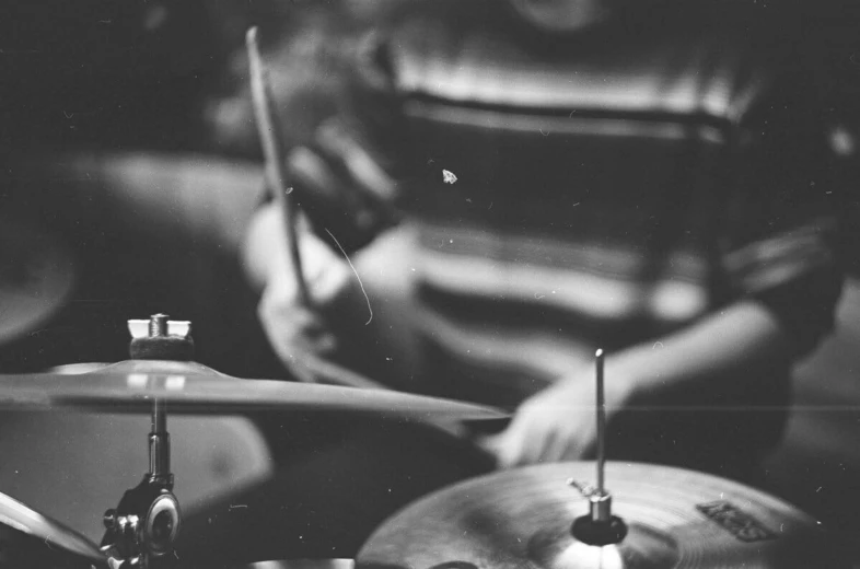 a black and white photo of a person playing drums, a black and white photo, unsplash, grainy damaged photo, tiny sticks, vinyl, [ realistic photography ]