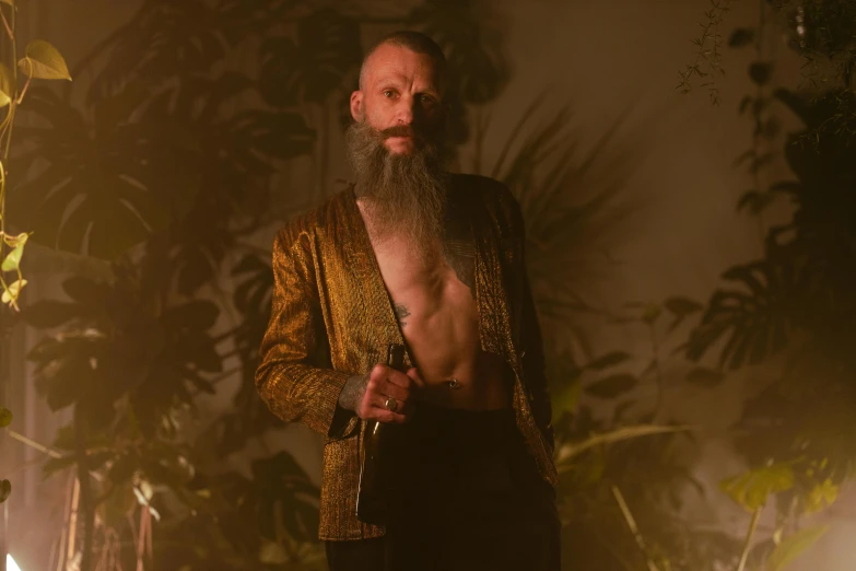 a man with a long beard wearing a gold jacket, an album cover, unsplash, lush surroundings, holding dagger, perfectly lit. movie still, shaved head