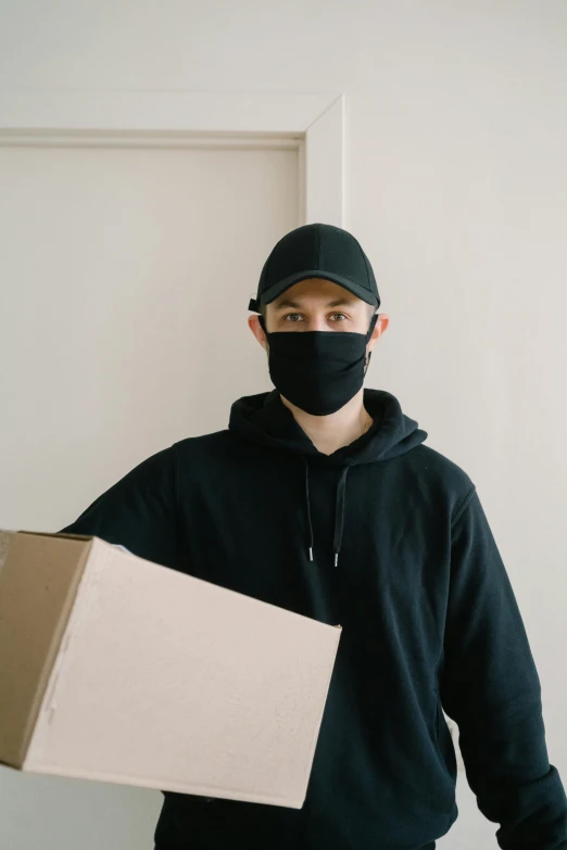 a man wearing a face mask holding a box, pexels contest winner, wearing black tight clothing, avatar image, leaving a room, headshot profile picture