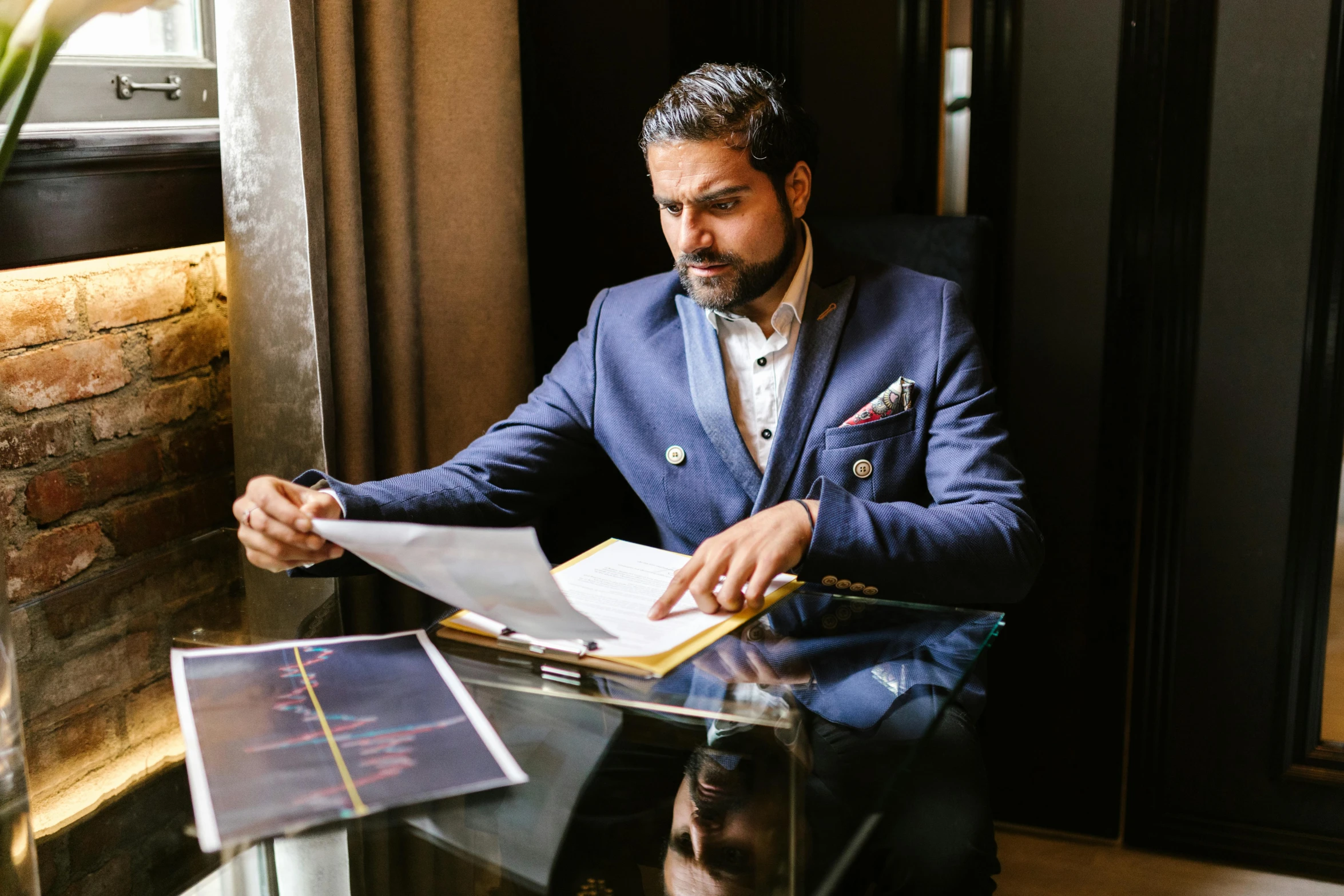 a man sitting in a chair reading a book, a portrait, pexels contest winner, hurufiyya, wearing a stylish men's suit, signing a bill, blue gold suit, a portrait of rahul kohli