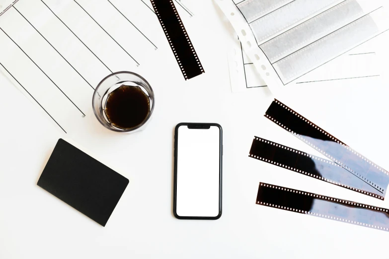 a cell phone sitting on top of a table next to film strips, trending on pexels, white minimalistic background, white and black color palette, curated collection, hq 4k phone wallpaper