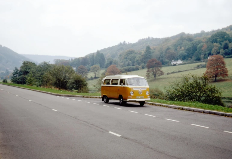 a yellow and white van driving down a road, unsplash, visual art, taken on a 1960s kodak camera, hills, hasselblad photo, colour photograph