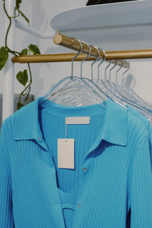 a blue shirt is hanging on a rack, a colorized photo, trending on unsplash, labels, sustainable materials, bright blue, victoria siemer