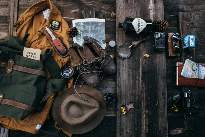 a backpack, hat, camera and other items laid out on a wooden surface, a portrait, trending on pexels, renaissance, leather hunting attire, camp, a handsome, thumbnail