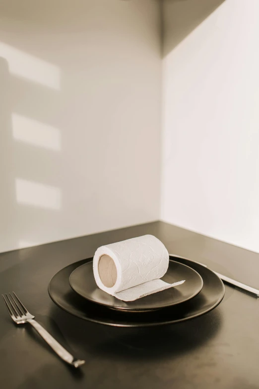 a plate with a roll of toilet paper on it, unsplash, dining table, matte black paper, high-quality photo, no text