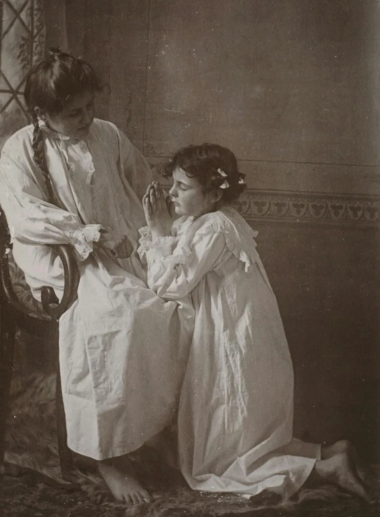 a couple of women standing next to each other, a black and white photo, by Nell Dorr, pre-raphaelitism, kneeling in prayer, wearing a hospital gown, young girl, promo image