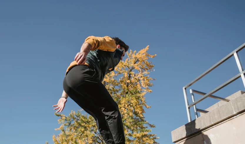 a man flying through the air while riding a skateboard, unsplash, figuration libre, parkour, autumnal, thumbnail, wearing track and field suit