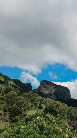 a man flying a kite on top of a lush green hillside, les nabis, towering cumulonimbus clouds, today\'s featured photograph 4k, rocky cliff, sri lanka