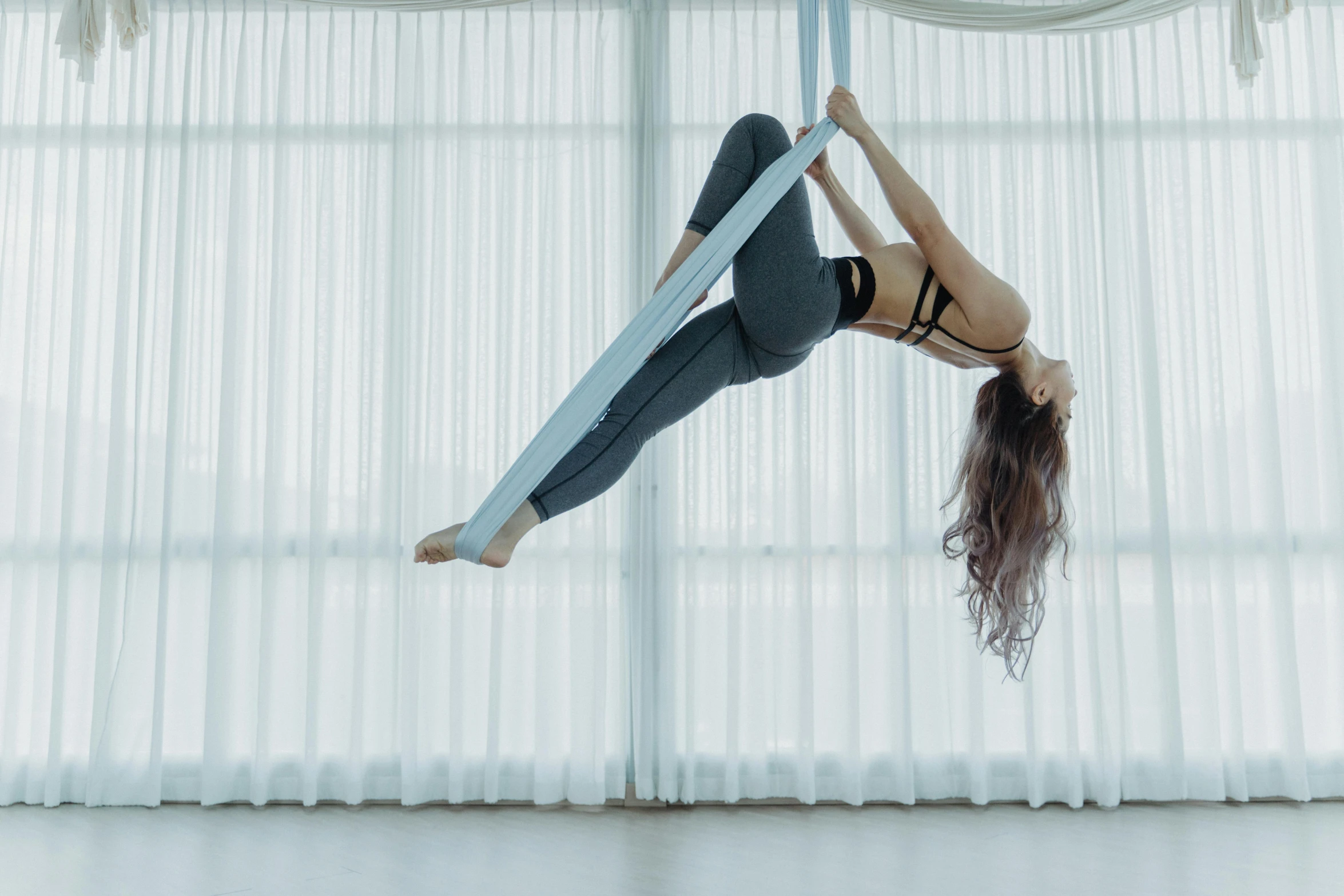 a woman flying through the air while holding onto a pole, pexels contest winner, arabesque, with screens and silks, aerial iridecent veins, back arched, sitting down