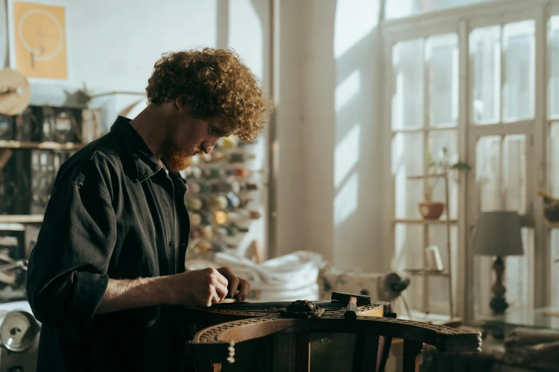 a man working on a piece of wood in a workshop, a portrait, by Thomas Furlong, pexels contest winner, arts and crafts movement, avatar image, hozier, on a white table, performance