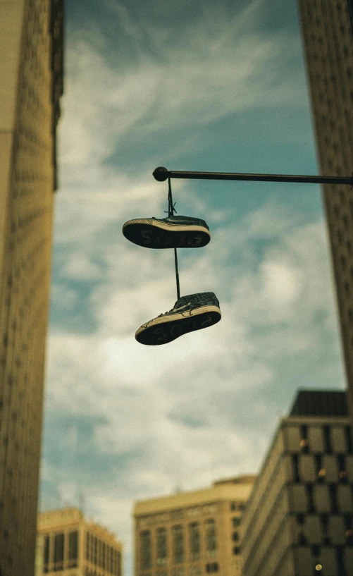 a pair of shoes hanging from a street light, unsplash, conceptual art, sneaker photo, multiple stories, low angle wide shot, [ cinematic