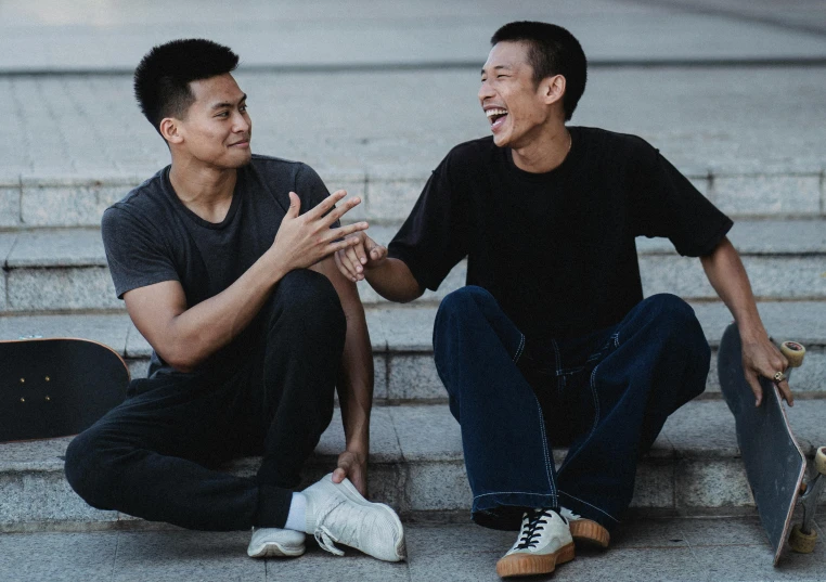 two men sitting on the steps with their skateboards, inspired by Wang Duo, pexels contest winner, smiling at each other, ruan jia and arthur rackham, half asian, reaching out to each other
