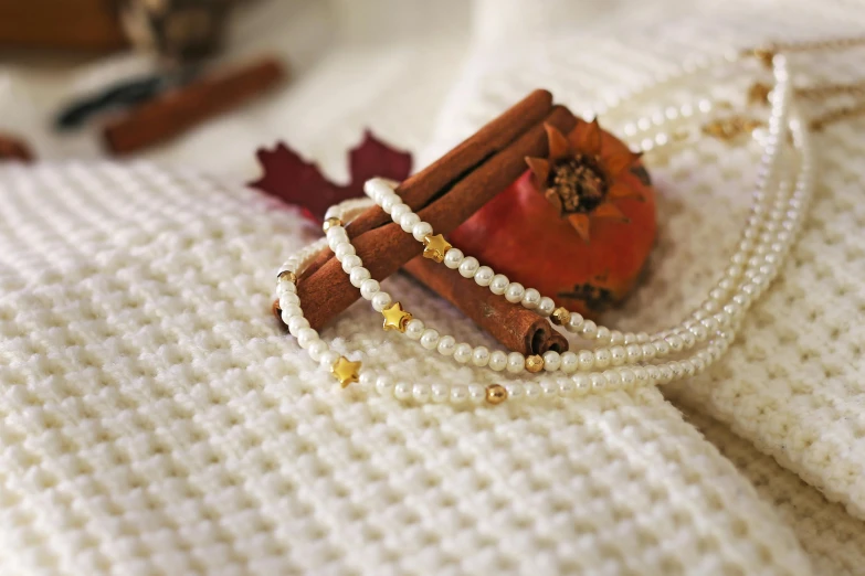 a red pomegranate sitting on top of a white blanket, inspired by Perle Fine, wearing gold detailed choker, in autumn, pearl necklace, stars