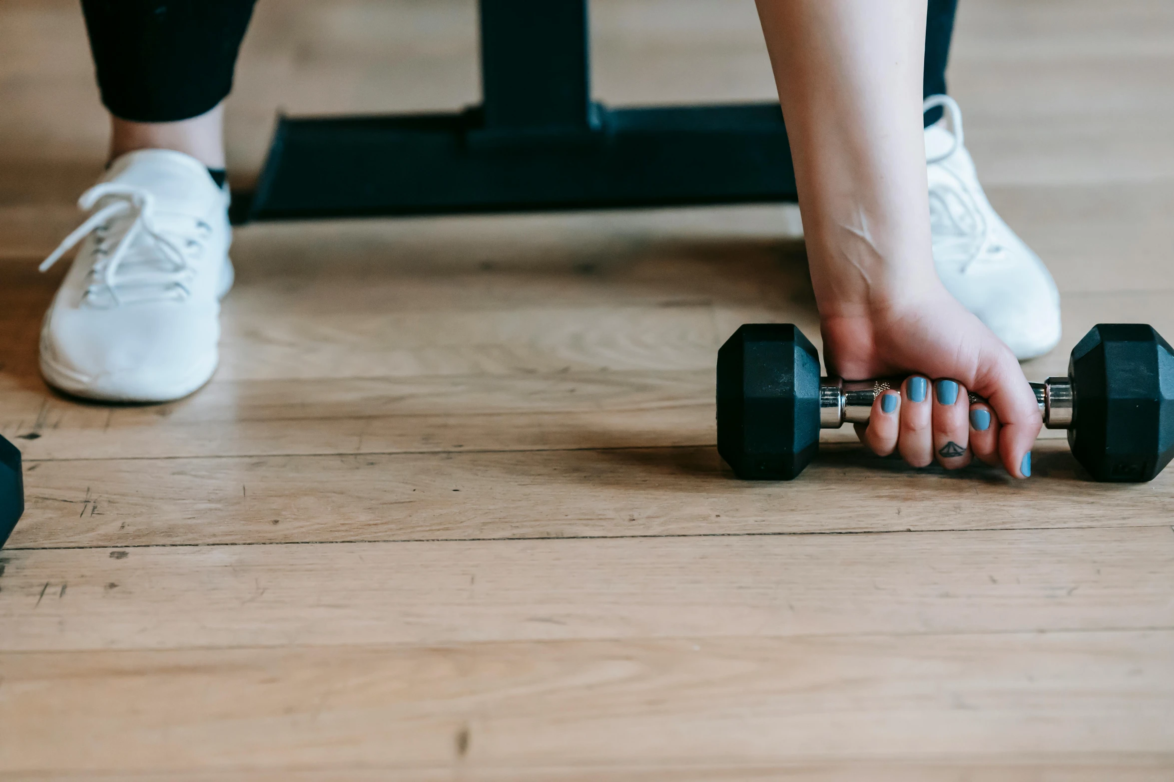 a person holding a pair of dumbs on a wooden floor, by Emma Andijewska, pexels contest winner, lifting weights, background image, manuka, dingy gym