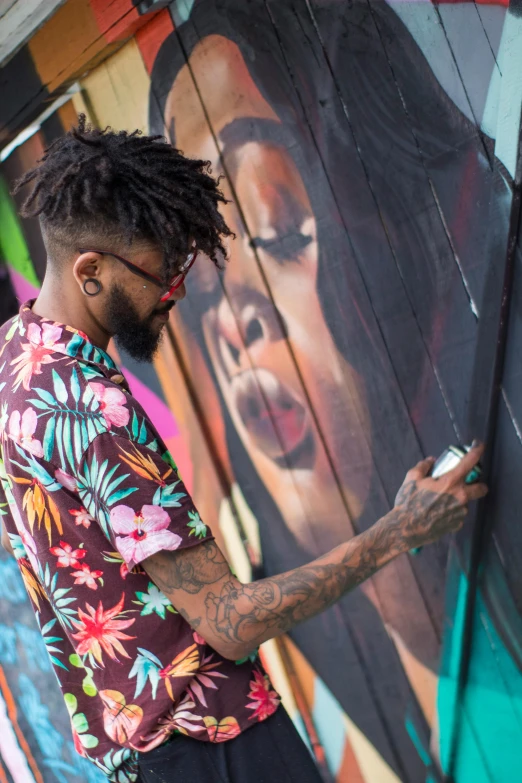 a man painting a mural on the side of a building, an airbrush painting, by artist, pexels contest winner, black arts movement, 2 1 savage, south beach colors, wood print, a person at a music festival