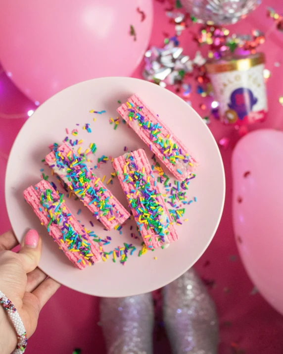 a person holding a plate with pink frosting and sprinkles, really long, parties, bismuth, thumbnail