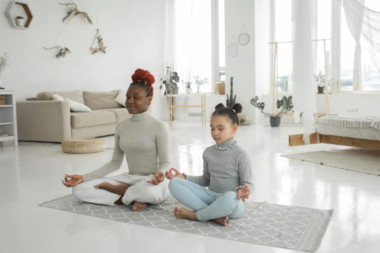 a woman and a child sitting on a rug in a living room, meditation pose, grey, two girls, good posture