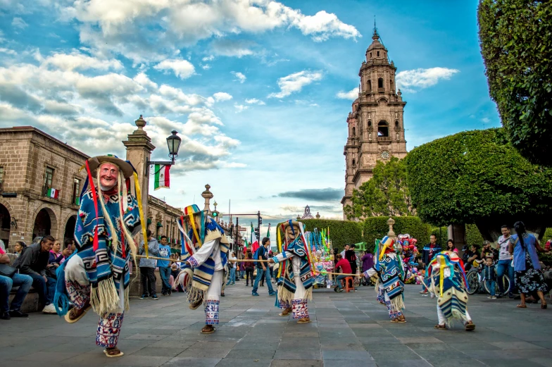 a group of people that are standing in the street, by Tom Wänerstrand, pexels contest winner, danza azteca dancers, cathedral in the background, square, listing image