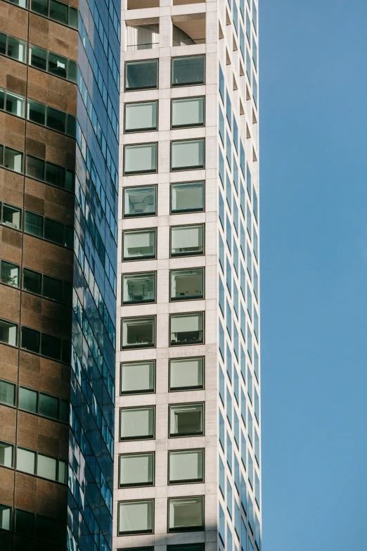 a couple of tall buildings next to each other, inspired by Ned M. Seidler, unsplash, hoog detail, clear blue skies, ignant, new york buildings