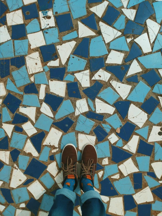 a person standing on a blue and white tiled floor, a mosaic, by Jessie Algie, trending on unsplash, sneaker photo, brown and cyan blue color scheme, in sao paulo, made of glazed