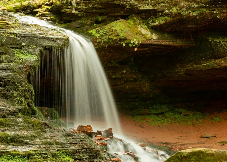 a small waterfall flowing through a lush green forest, by Kristin Nelson, pexels contest winner, red sandstone natural sculptures, alabama, cave with waterfall, sandfalls