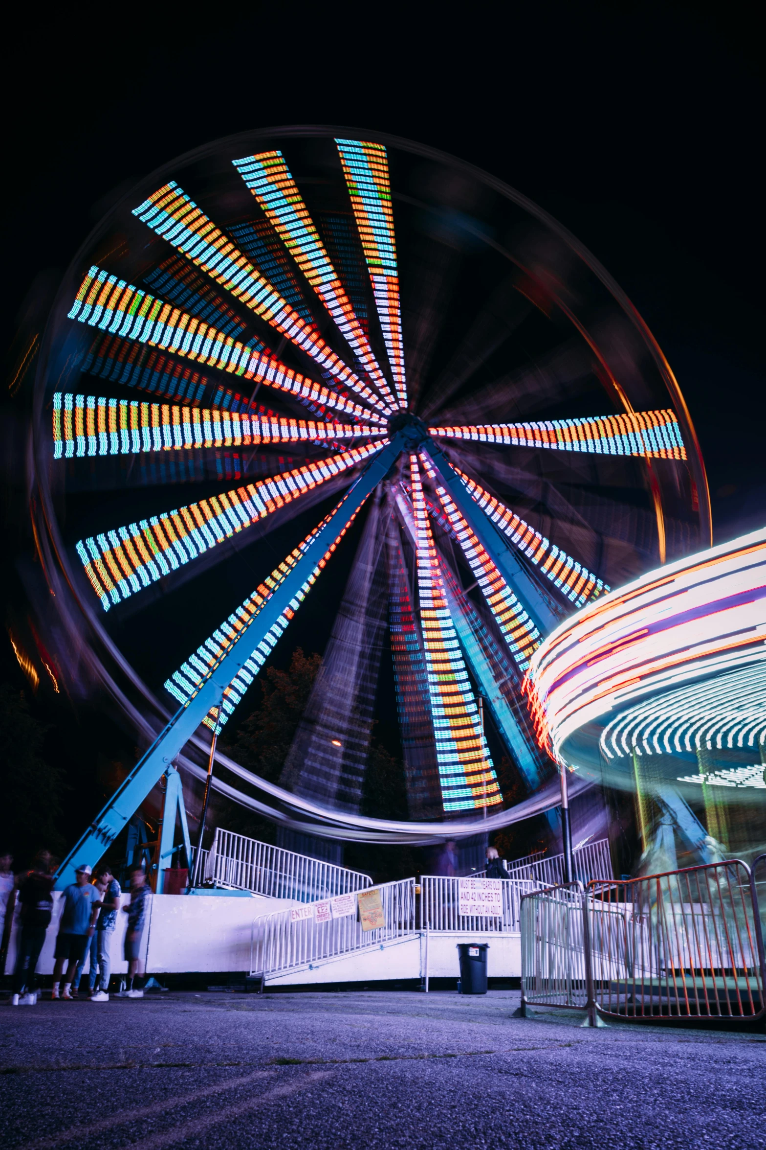 a ferris wheel and a ferris wheel at night, pexels contest winner, kinetic art, blurry footage, color image, lightshow, night time footage