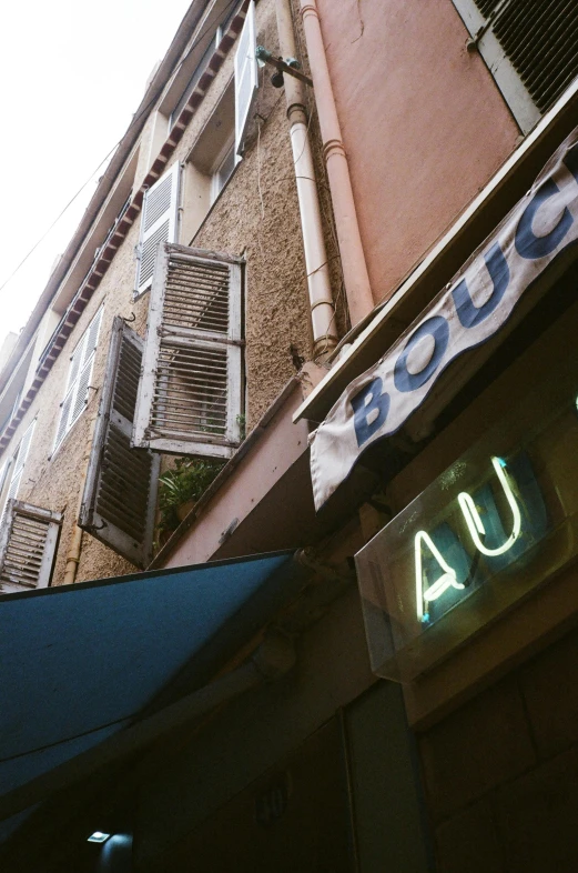 a sign that is on the side of a building, inspired by Auguste Baud-Bovy, unsplash, art nouveau, des boutiques avec des neons, nice afternoon lighting, alley, sougetsu