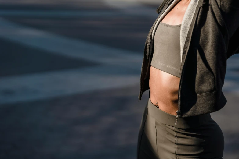 a woman standing on a city street talking on a cell phone, an album cover, by Nina Hamnett, trending on pexels, renaissance, sport bra, physical : tinyest midriff ever, texture detail, sport clothing