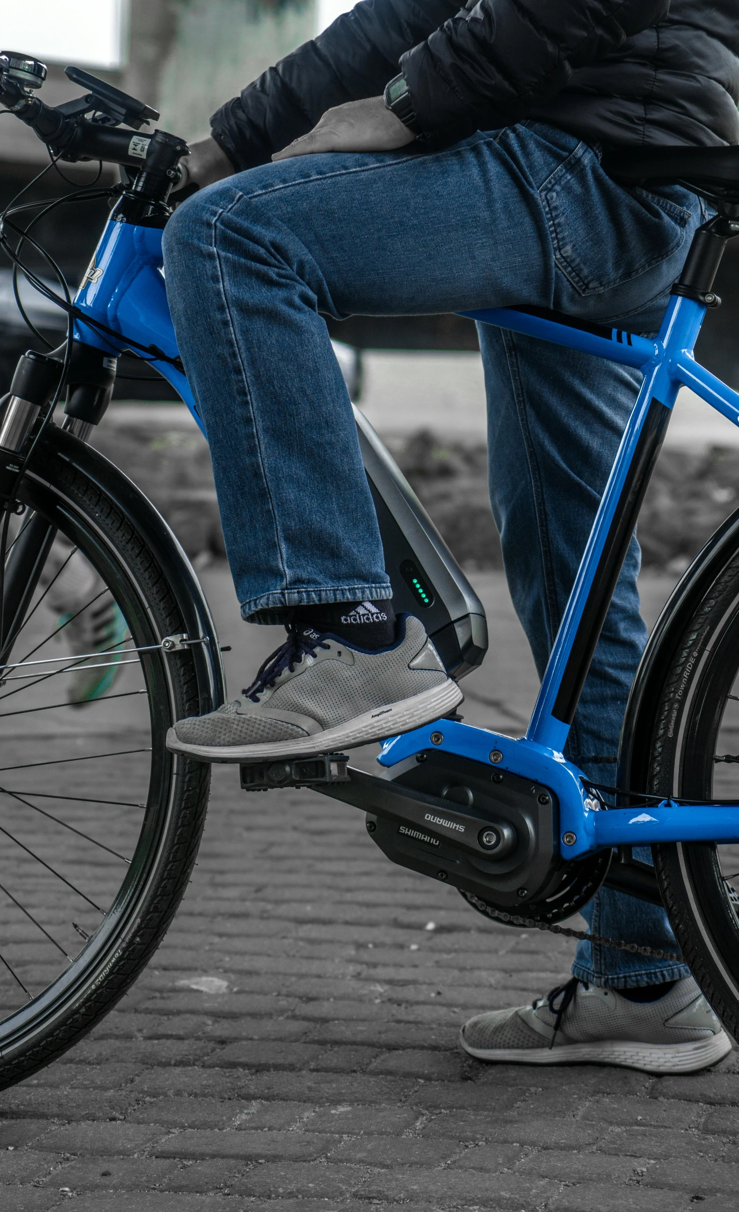 a man sitting on top of a blue bike, gray shorts and black socks, zoomed in, whole shoe is in picture, profile image