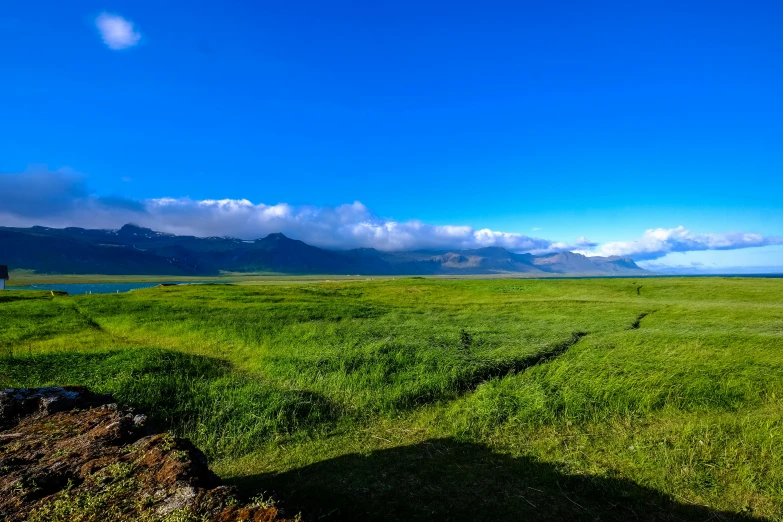 a grassy field with mountains in the background, by Julia Pishtar, unsplash, hurufiyya, cloudless-crear-sky, inlets, background image, volcanic landscape