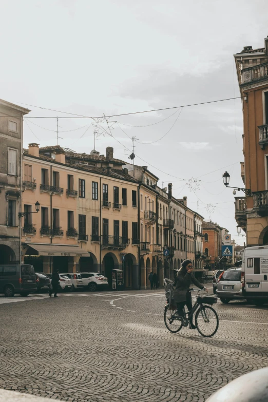 a man riding a bike down a street next to tall buildings, inspired by Gaetano Sabatini, pexels contest winner, renaissance, running through italian town, small town surrounding, on a great neoclassical square, paisley