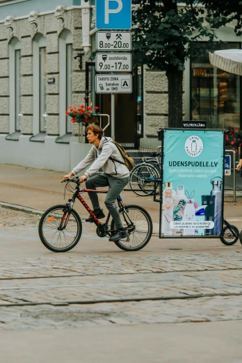 a person riding a bike on a city street, a poster, pexels contest winner, finland, digital billboards, cardboard, hydrogen fuel cell vehicle