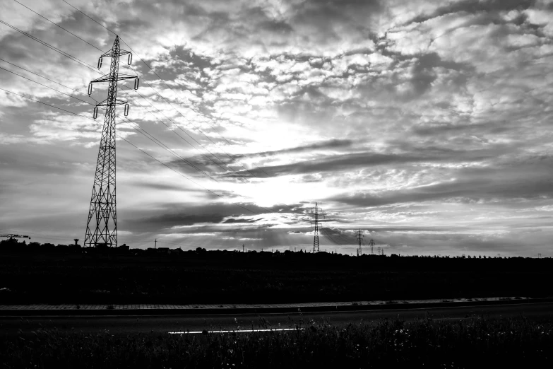 a black and white photo of power lines, a black and white photo, by Kristian Zahrtmann, pexels, sunset with cloudy skies, high quality upload, a green, towers