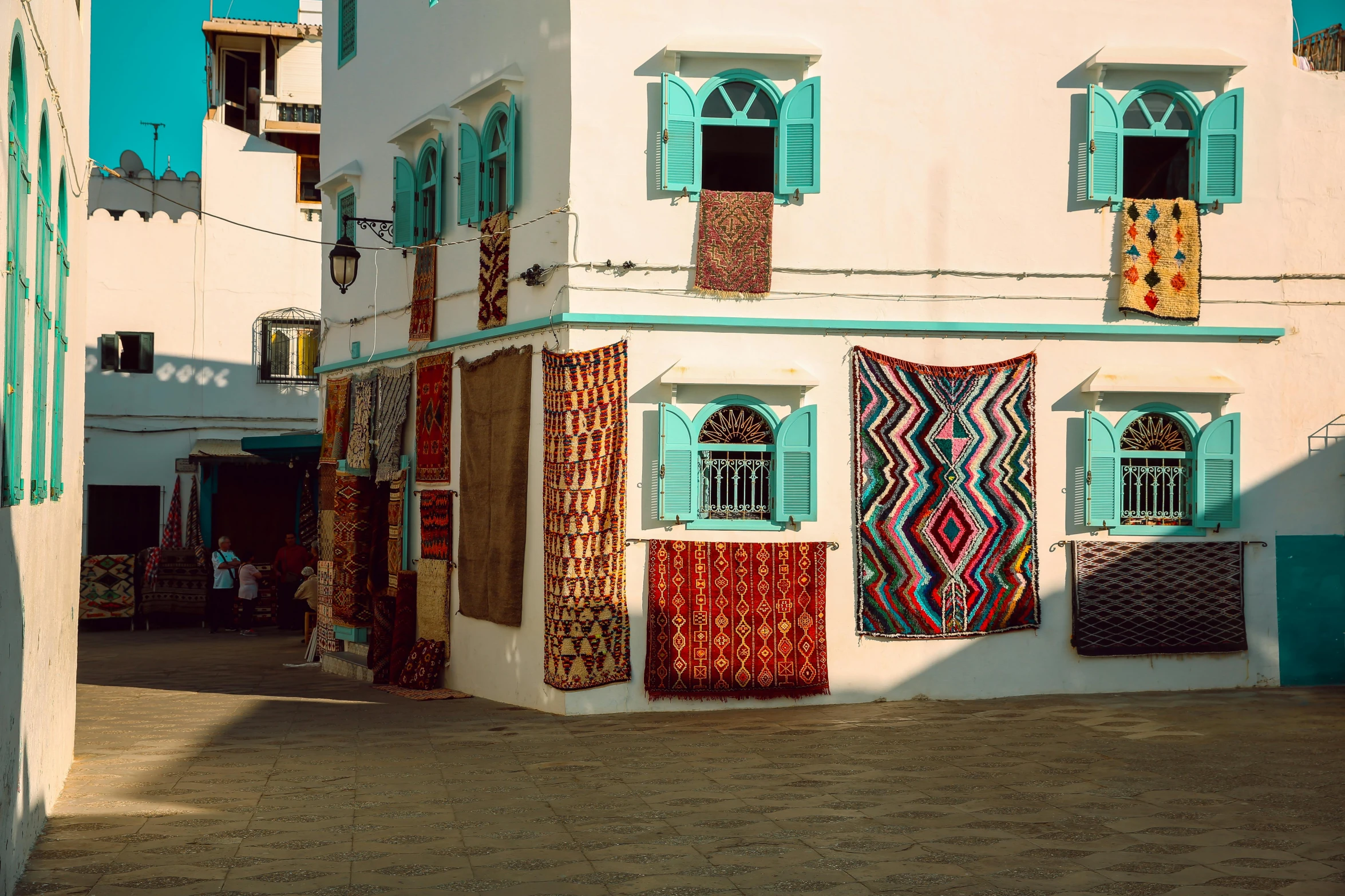 a building that has a lot of rugs on it, inspired by Alberto Morrocco, unsplash contest winner, white houses, street of teal stone, nubian, unsplash photo contest winner