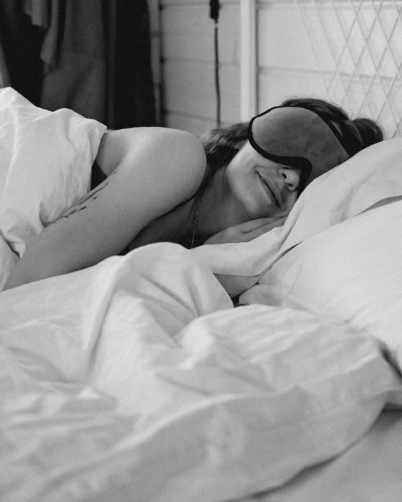 a black and white photo of a woman laying in bed, a black and white photo, by Anita Malfatti, pexels, black eye mask, ffffound, 1 9 6 0 s, summer morning