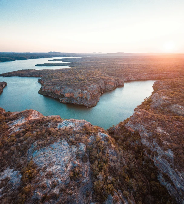 a large body of water surrounded by trees, pexels contest winner, australian tonalism, the planet is warm with canyons, golden hour 8 k, bird\'s eye view, epic land formations