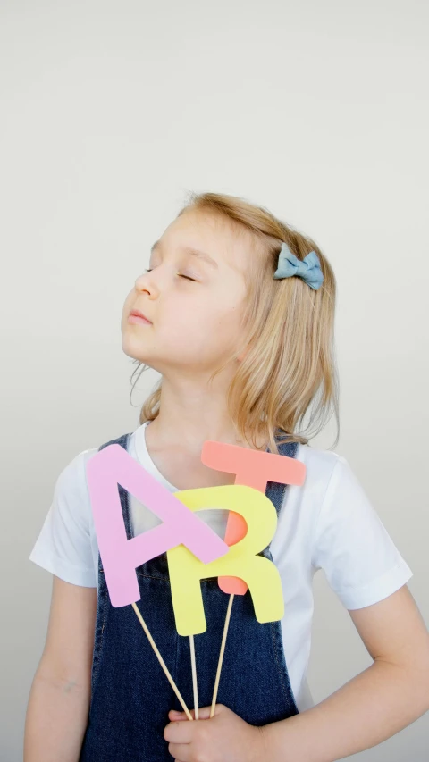 a little girl that is holding some paper numbers, pexels, letterism, wearing hair bow, low quality photo, pastel', schools