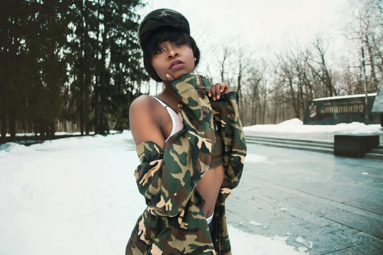 a woman posing for a picture in the snow, an album cover, inspired by Elsa Bleda, trending on pexels, visual art, camouflage uniform, black young woman, street wear, camouflage made of love