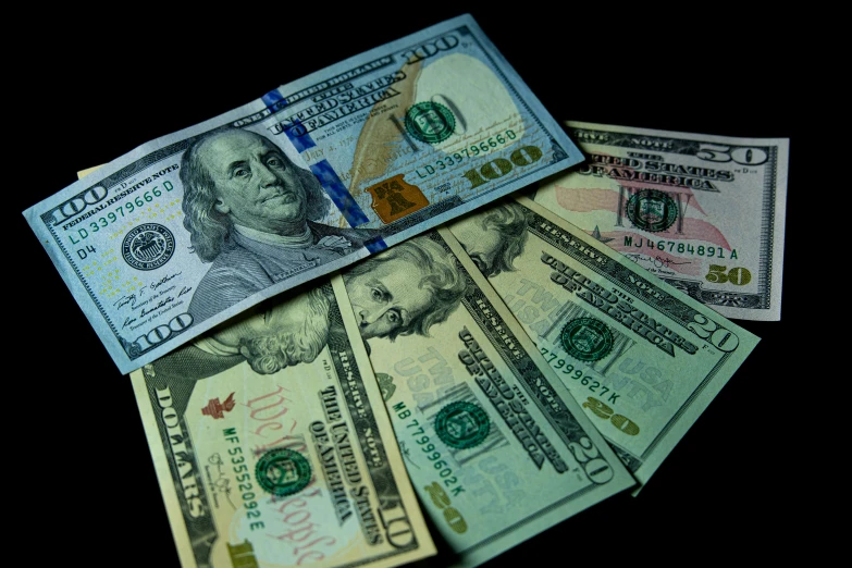 a pile of money sitting on top of a table, in front of a black background, american total portrait, thumbnail, multicolored