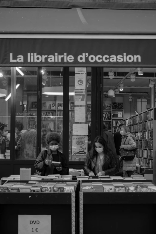 a couple of people standing in front of a book store, a black and white photo, by Raphaël Collin, covid, tending on arstation, vast library, decorated