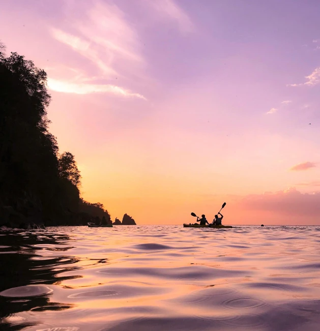 a couple of people riding kayaks on top of a body of water, by Jessie Algie, pexels contest winner, romanticism, purple sunset, a photo of the ocean, lush surroundings, conde nast traveler photo