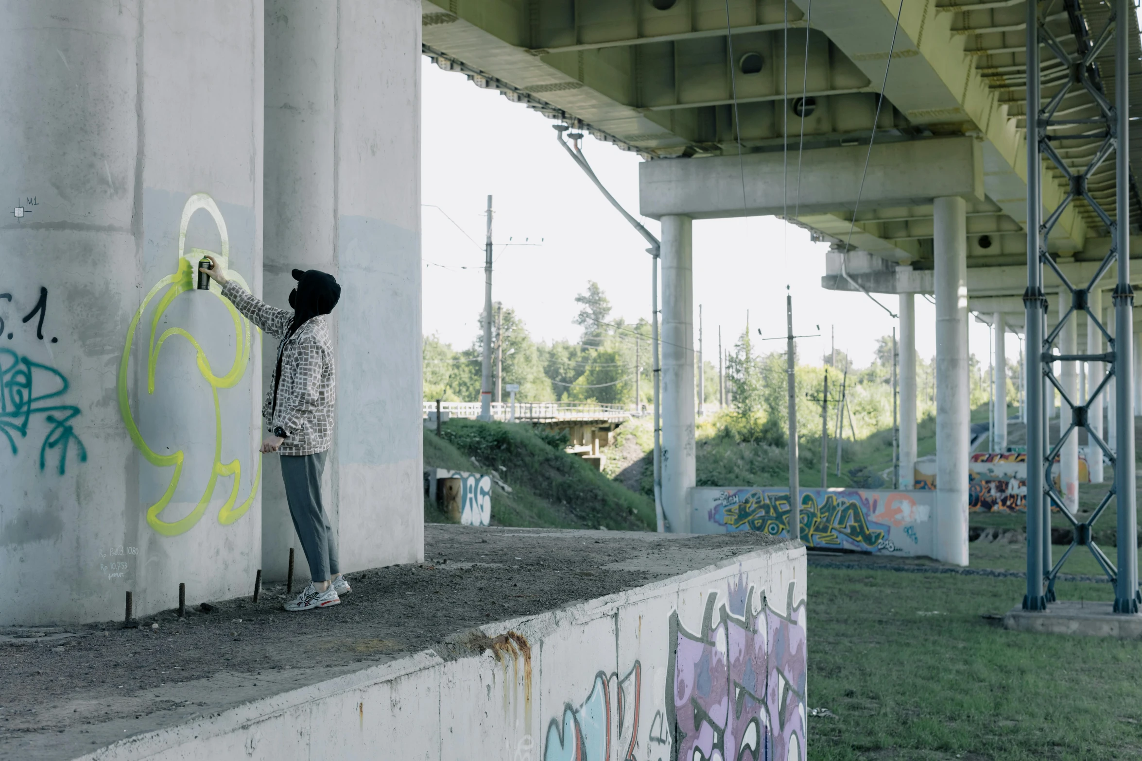 a person painting graffiti on a wall under a bridge, still from l'estate, fromme seele, seen in the distance, malika favre