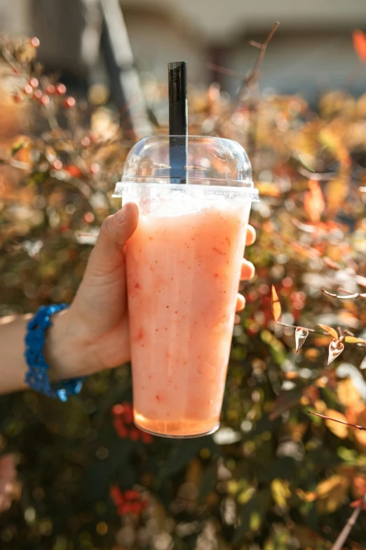 a person holding a plastic cup with a drink in it, peach, jc park, frosted, large cornicione