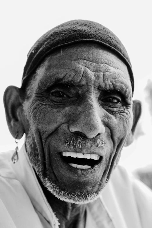 a black and white photo of an old man, hurufiyya, large black smile, brown skin man with a giant grin, in socotra island, right - half a cheerful face