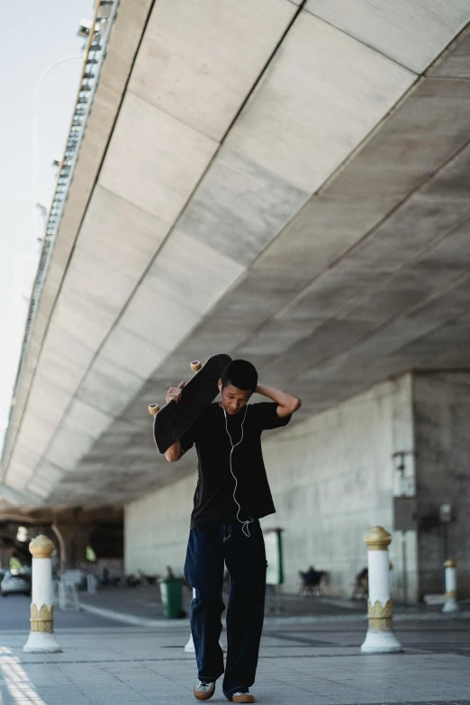 a man riding a skateboard under a bridge, a picture, unsplash, hunched shoulders, bassist, asian man, pondering