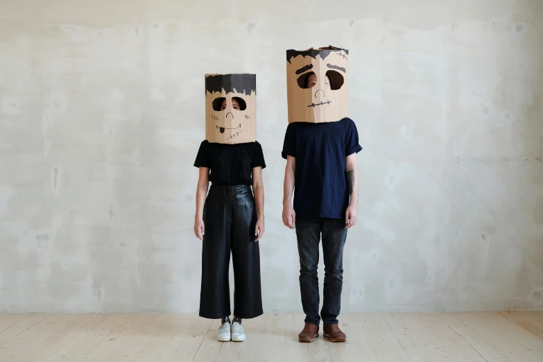 two people standing next to each other with paper bags on their heads, by Nina Hamnett, conceptual art, full skull shaped face cover, robot made of a cardboard box, boy and girl, with black